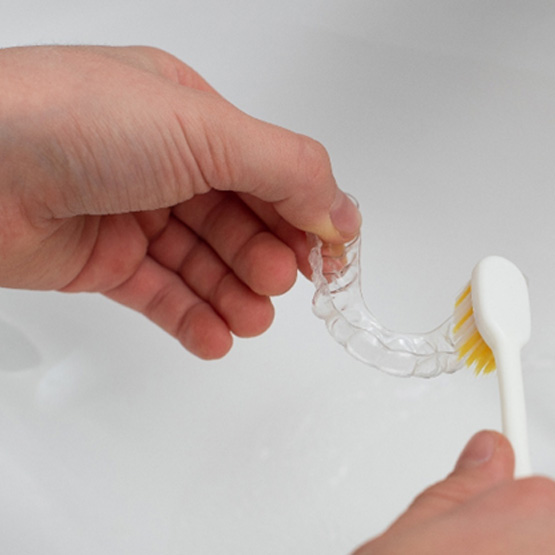 Person cleaning their clear aligners easily